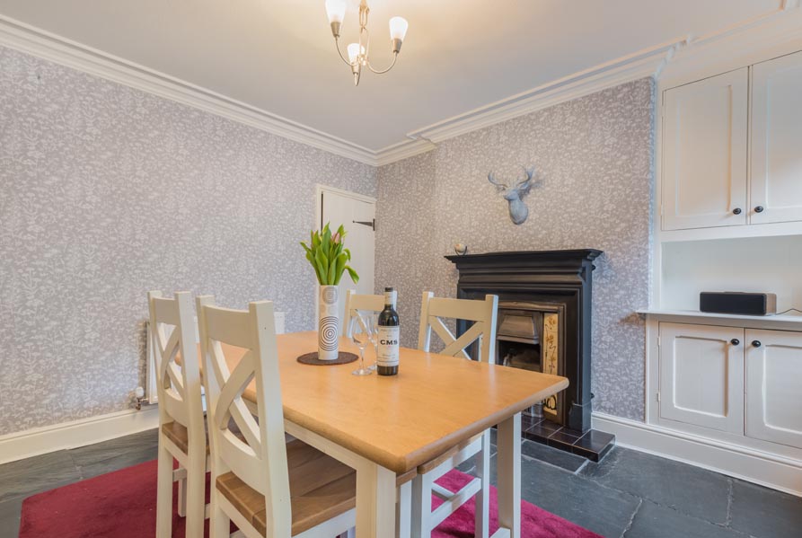 Dining table with four chairs beside the traditional fireplace