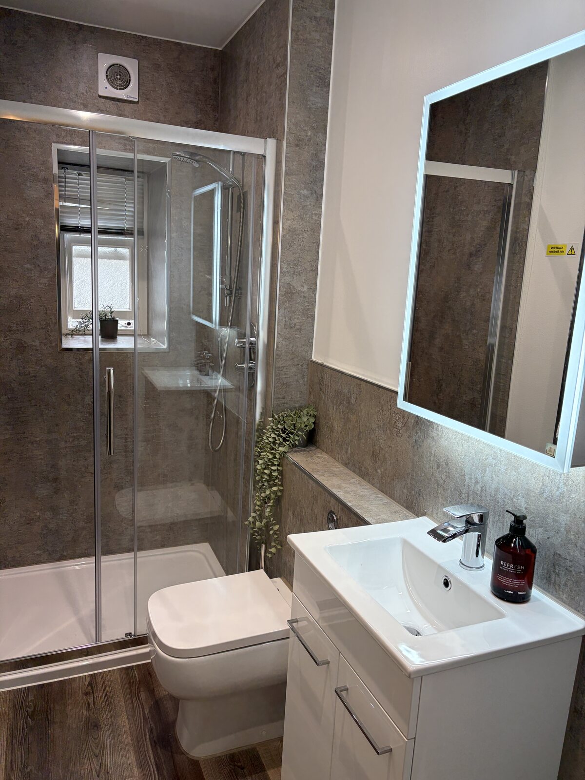 Modern shower room with walk-in shower, toilet, vanity basin and illuminated mirror